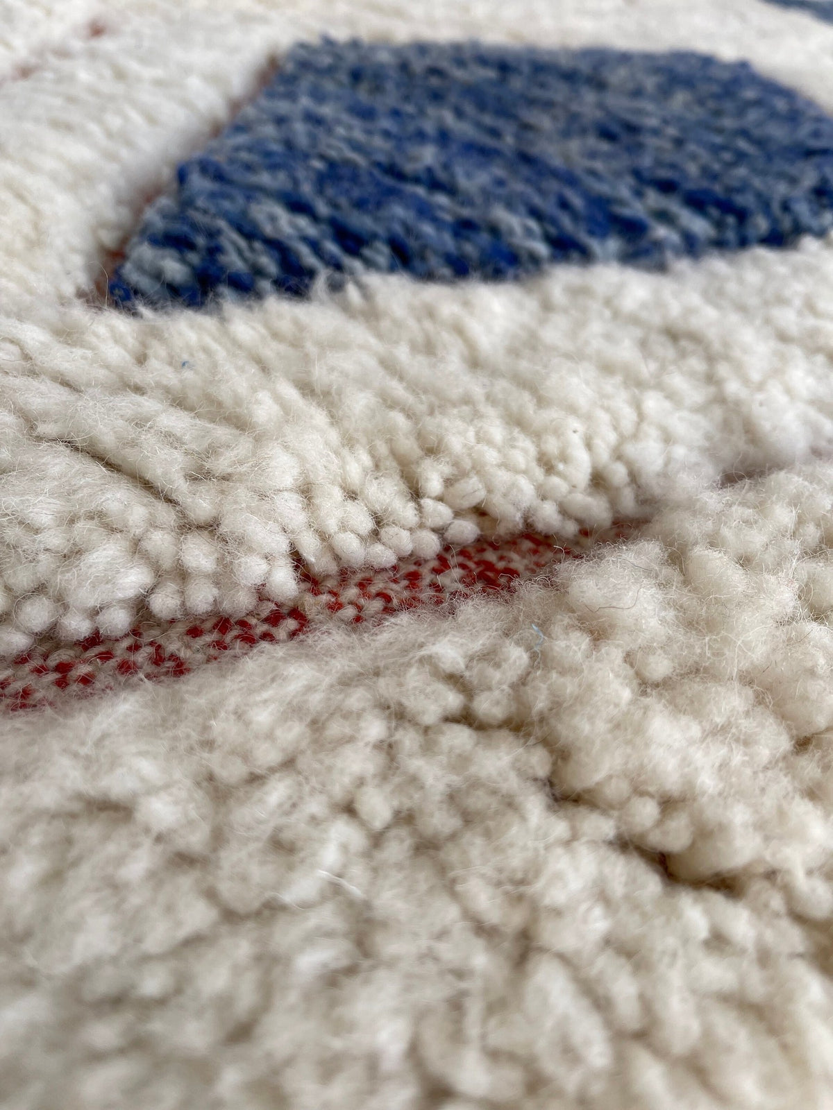 Gros plan sur la laine du tapis berbère Aman, texture de la laine naturelle et nuances du poil