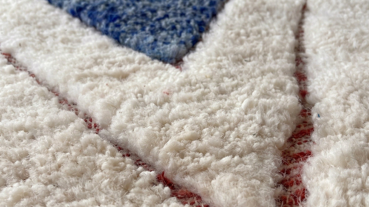 Gros plan sur la laine du tapis berbère Aman, poil blanc et bleu noué à la main