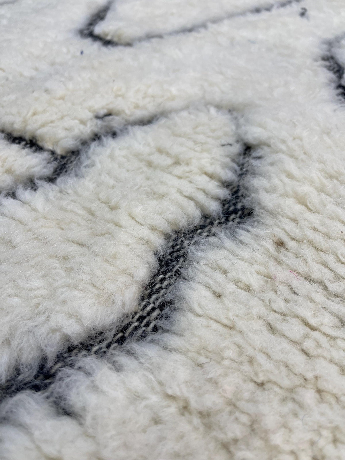 Gros plan sur la laine du tapis berbère Elzira, nœuds serrés et tracé du motif de près
