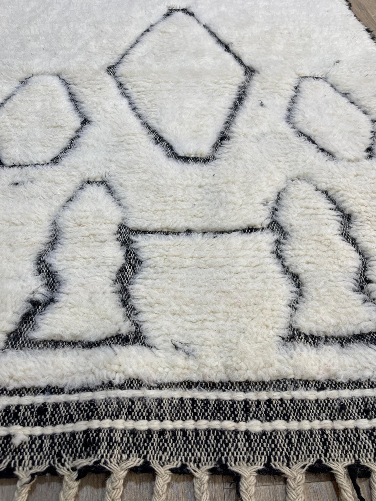 Gros plan sur un détail du tapis berbère Elzira, poil long et motif blanc et noir vus de près