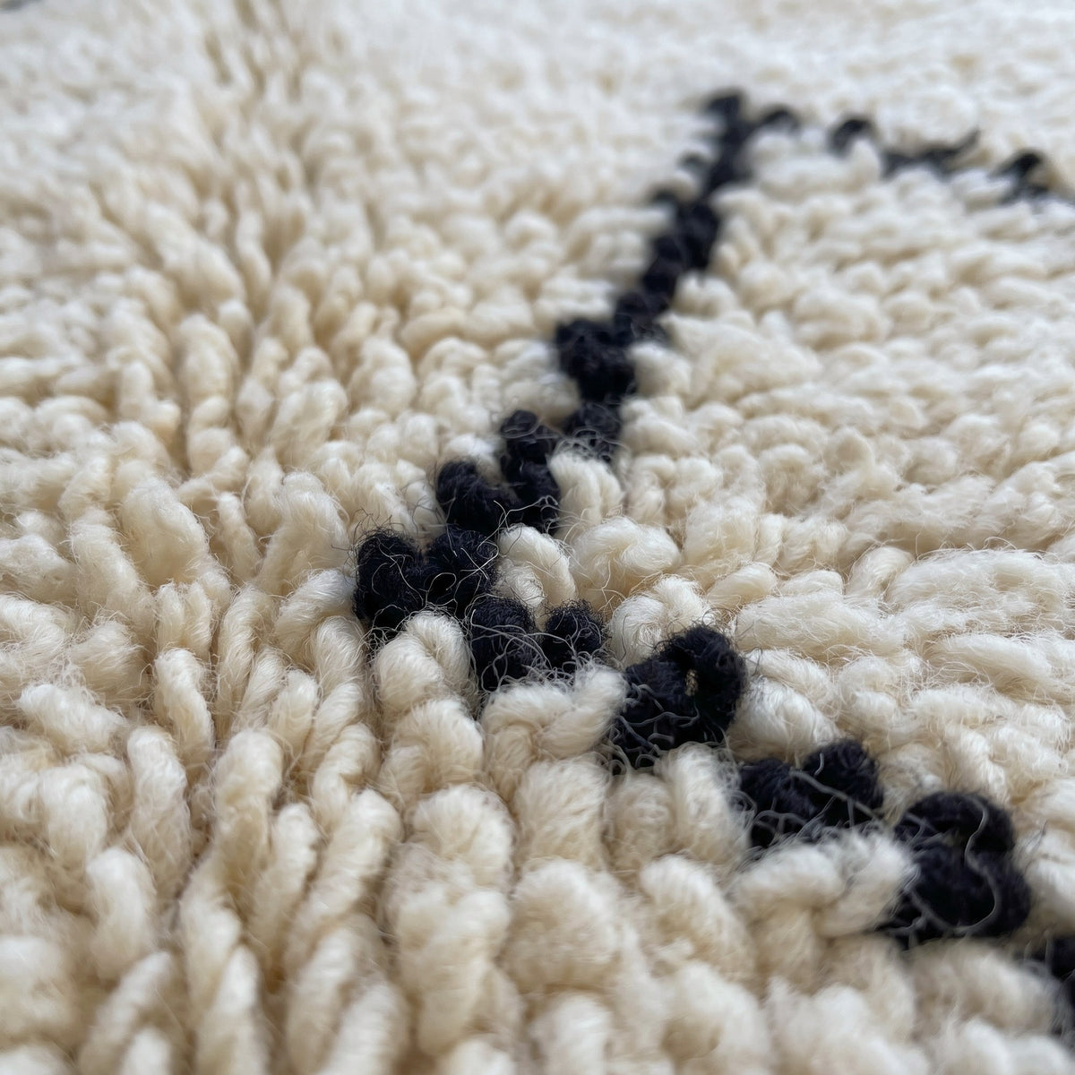 Gros plan sur un motif du tapis berbère Elzira, style Beni Ouarain à poil long bouclé