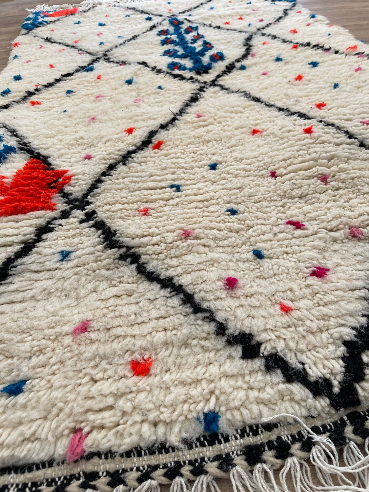 Gros plan sur un détail du tapis berbère Idmim, poil long et motif blanc et noir vus de près