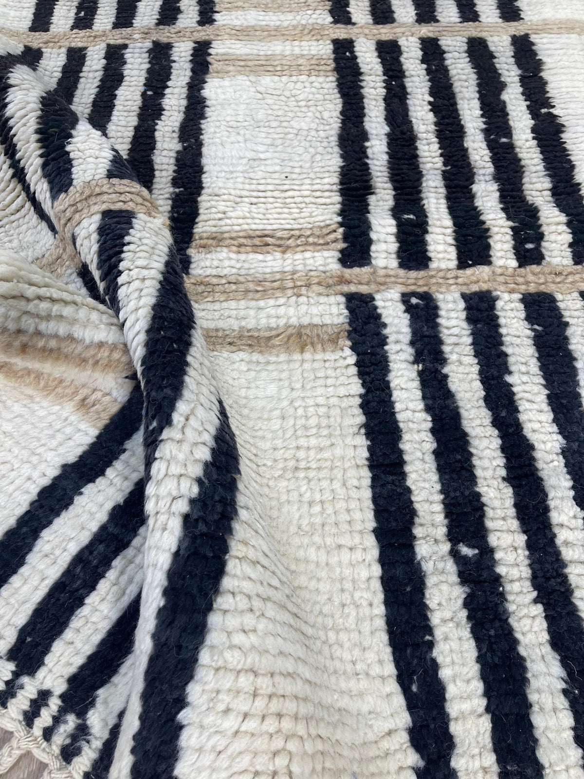 Gros plan sur la laine du tapis berbère Kelti, laine de mouton au poil long, blanche et noire
