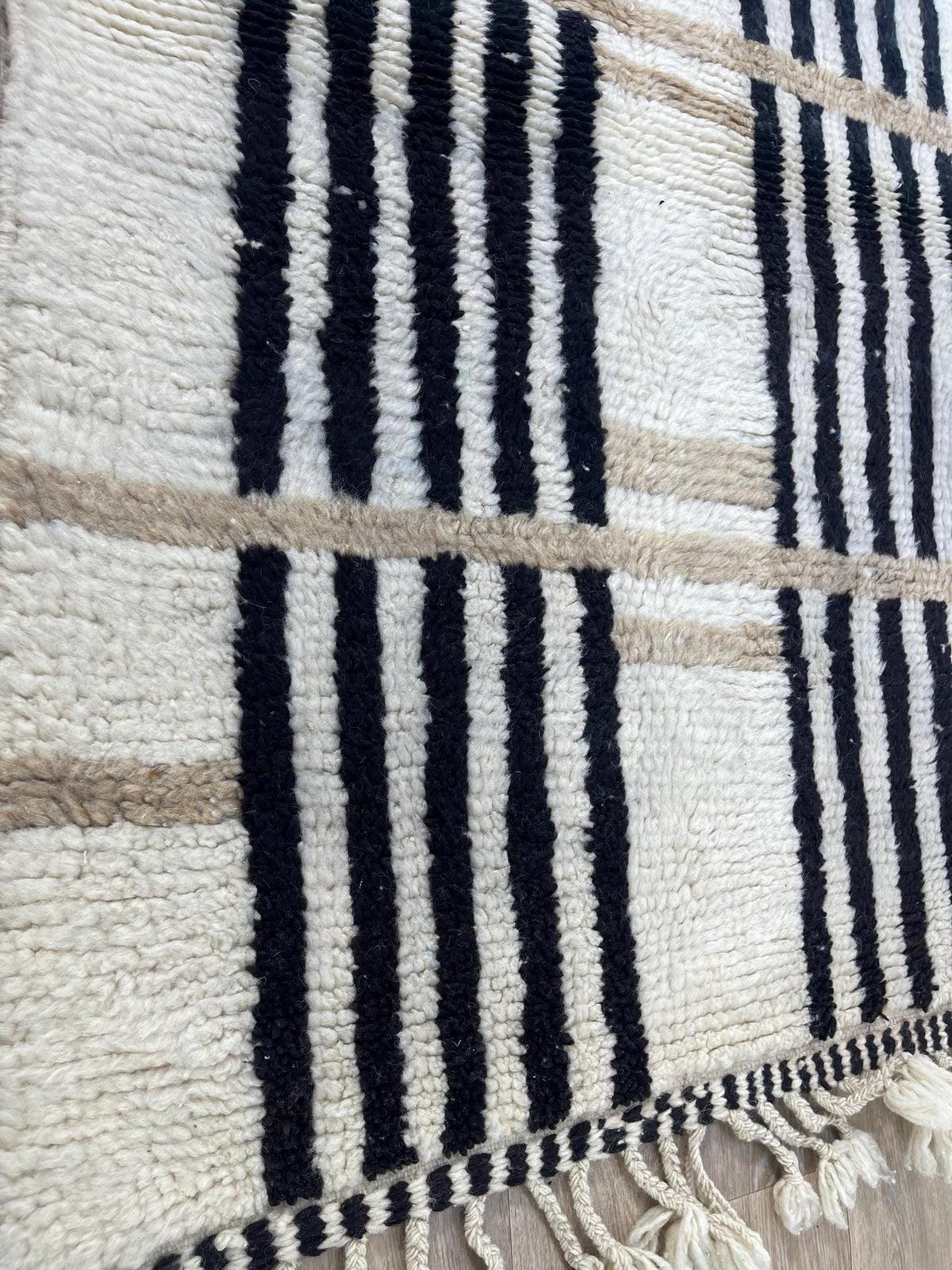 Gros plan sur un détail du tapis berbère Kelti, poil long et motif blanc et noir vus de près