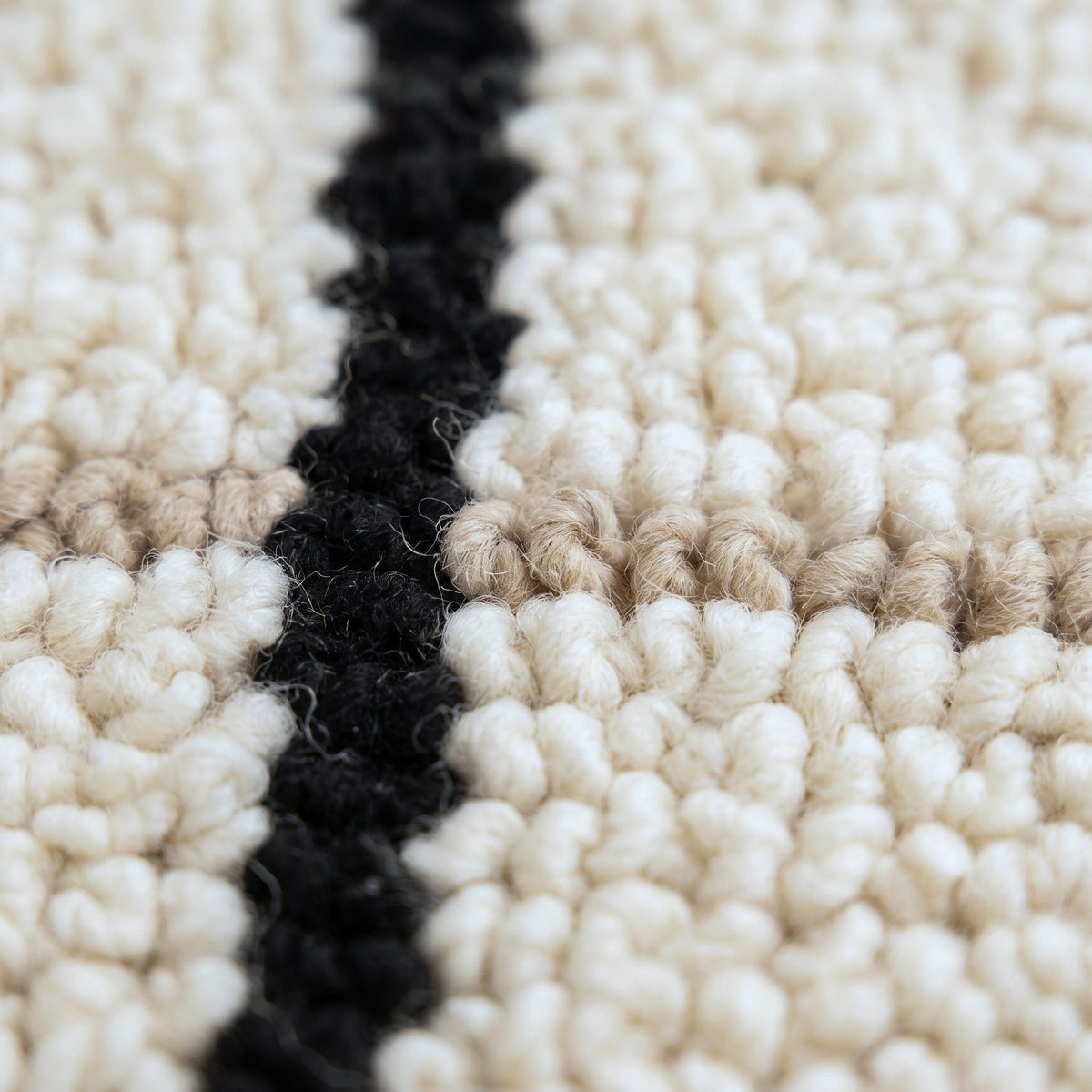 Gros plan sur un motif du tapis berbère Kelti, fond ivoire, deux faisceaux verticaux de cinq rayures
