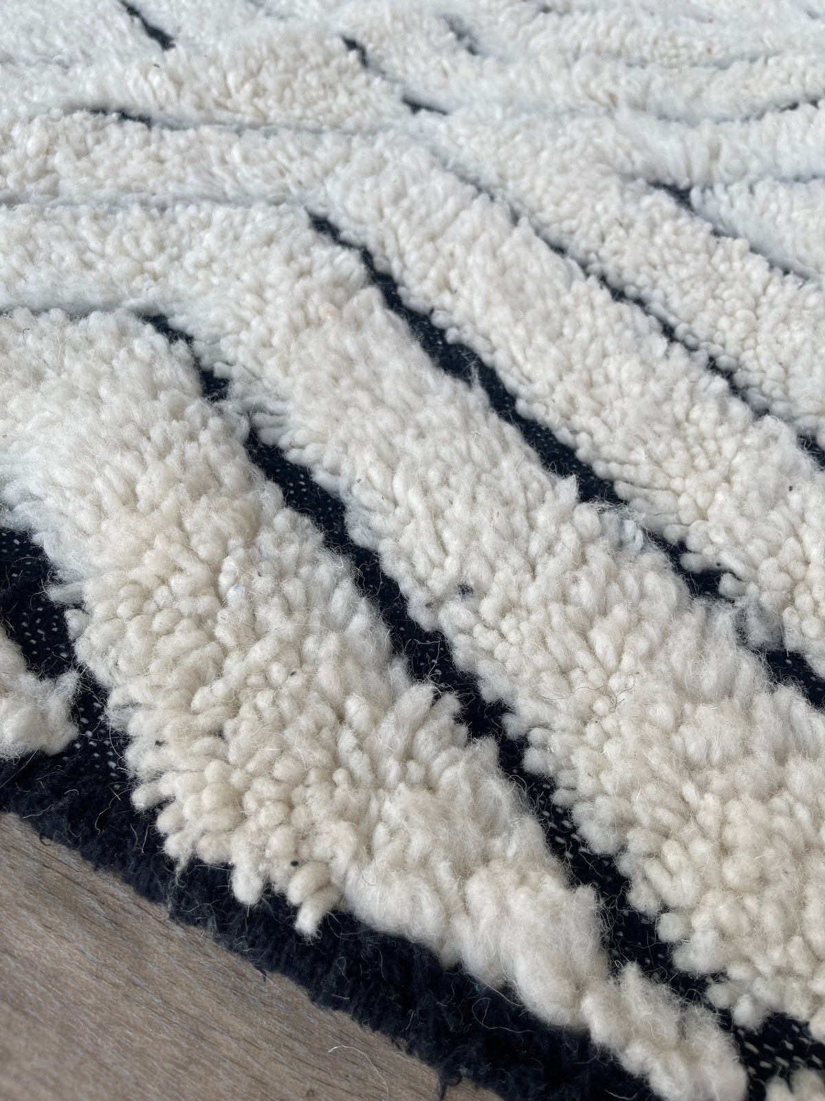 Gros plan sur la laine du tapis berbère Ousmil, nœuds serrés et tracé du motif de près