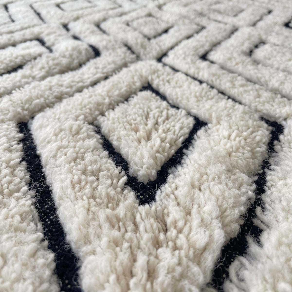 Gros plan sur un motif du tapis berbère Ousmil, fond ivoire à poil long en relief