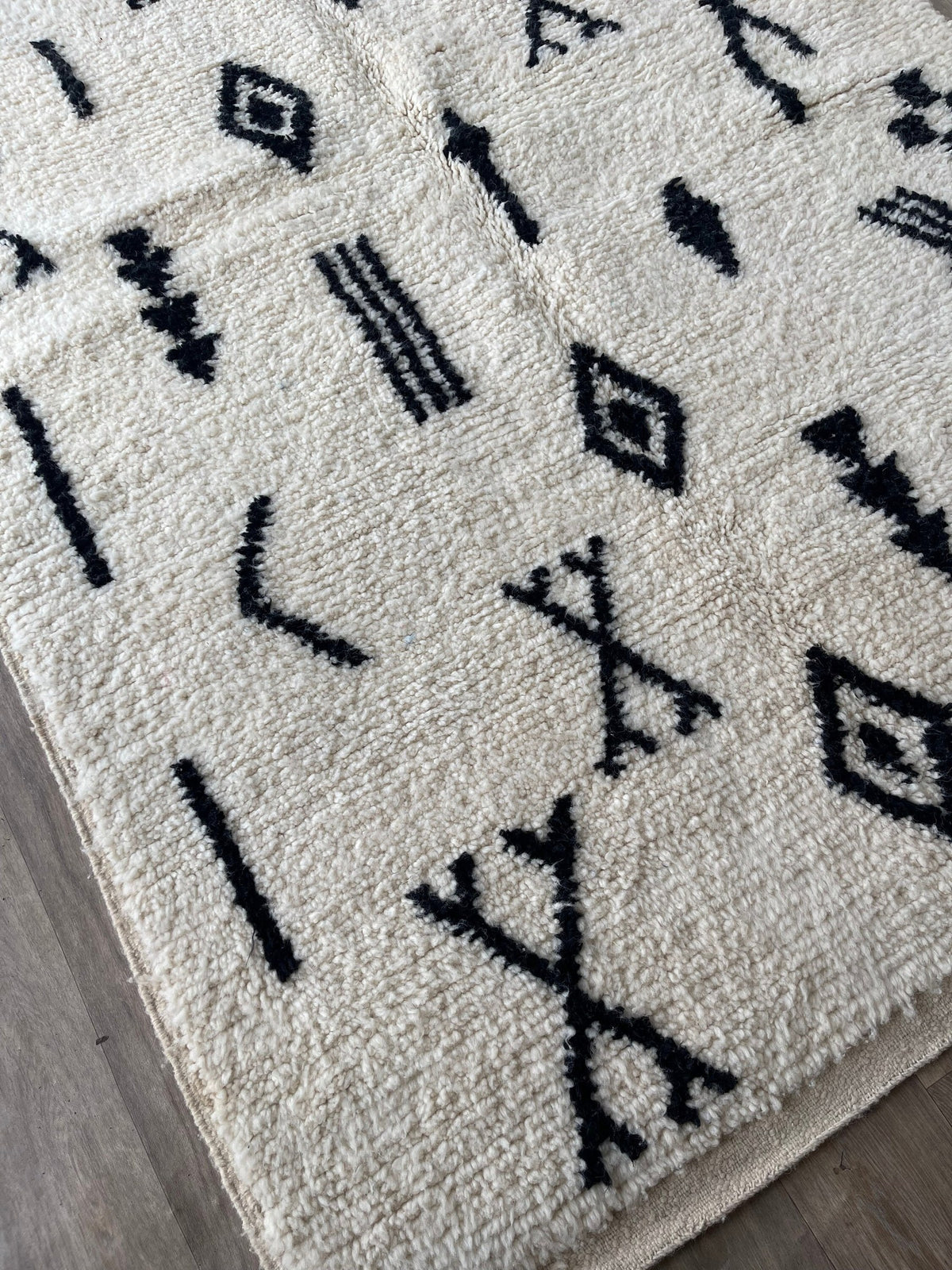 Gros plan sur le coin relevé du tapis berbère Tasusmi, épaisseur du poil long et dos tissé à la main
