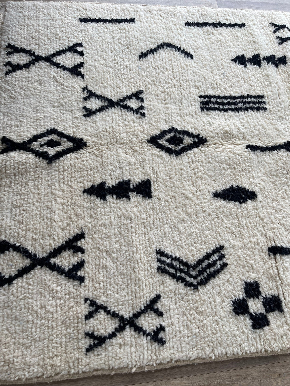 Gros plan sur la laine du tapis berbère Tasusmi, laine de mouton au poil long, blanche et noire