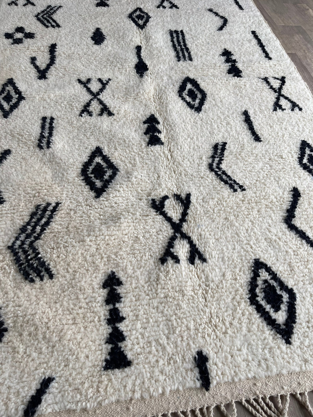 Gros plan sur un détail du tapis berbère Tasusmi, poil long et motif blanc et noir vus de près