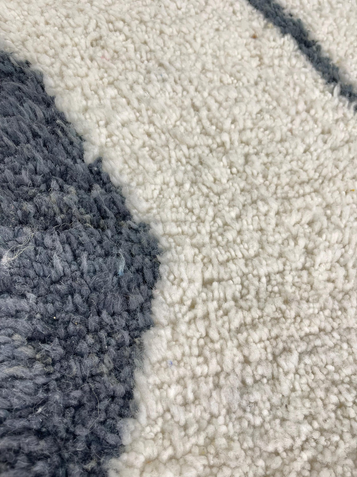 Gros plan sur la laine du tapis berbère Tiziri, poil blanc et noir noué à la main