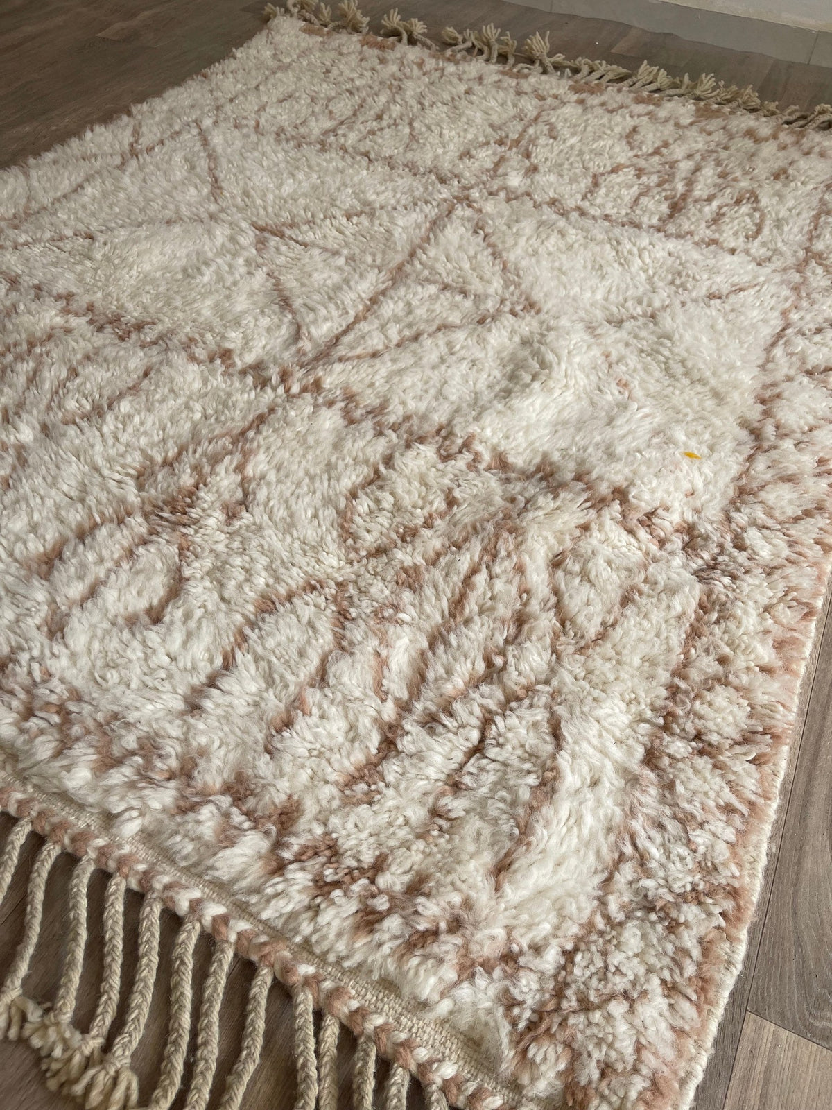 Tapis berbère style Beni Ouarain blanc et rose Timoulay posé au sol vu de côté, noué main au Maroc