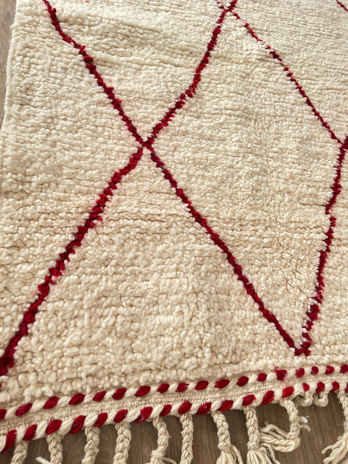 Gros plan sur les franges du tapis berbère Tanemmirt, écrues en bas, nouées à la main