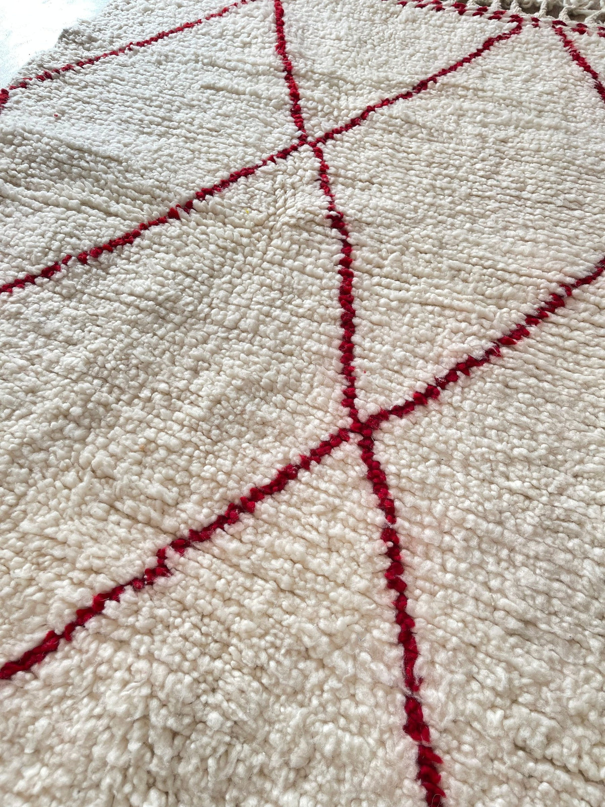 Gros plan sur la laine du tapis berbère Tanemmirt, nœuds serrés et tracé du motif de près