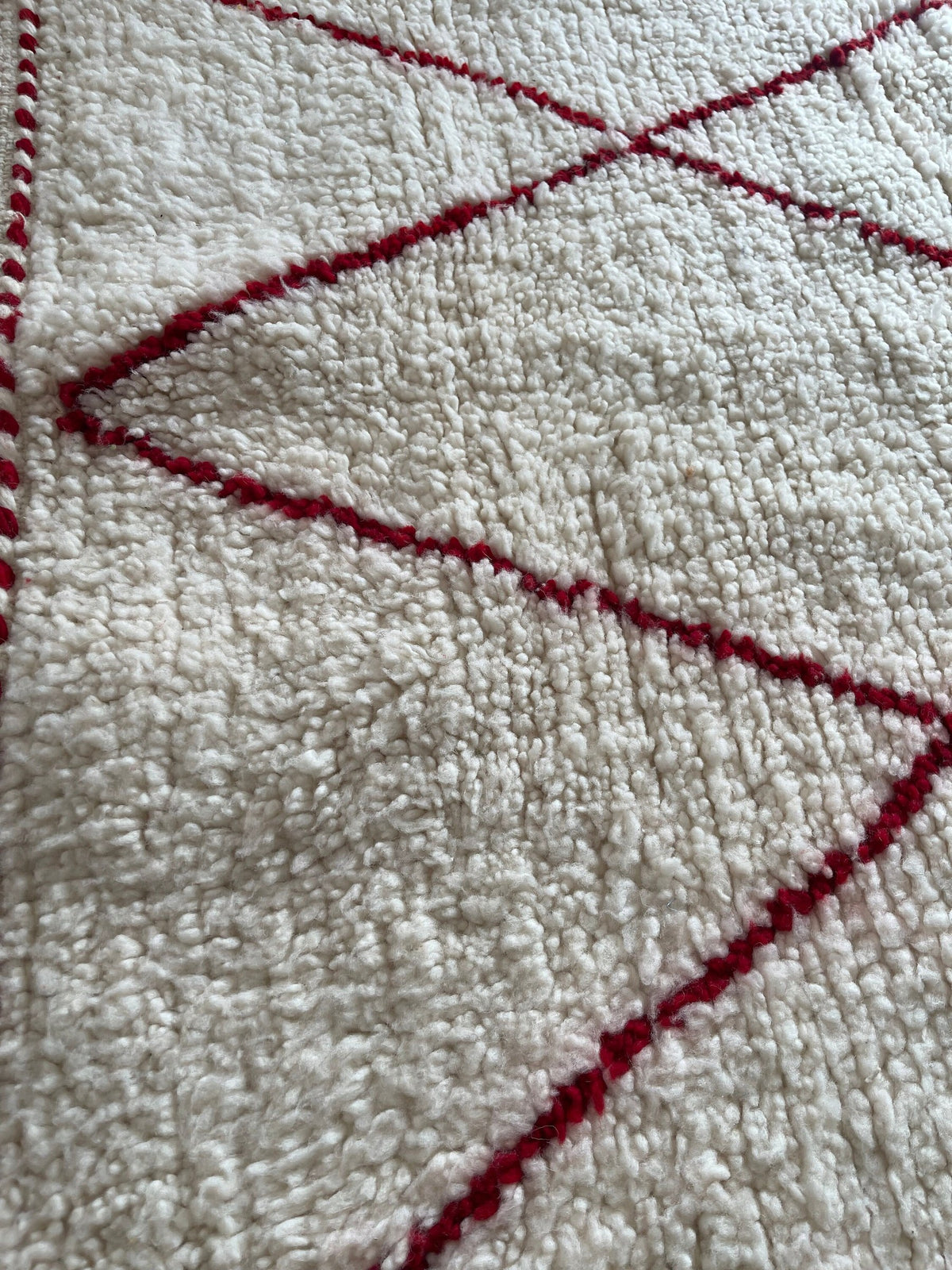 Gros plan sur la laine du tapis berbère Tanemmirt, poil blanc et rouge noué à la main