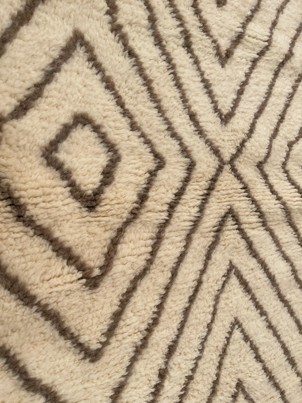 Gros plan sur la laine du tapis berbère Almis, laine de mouton au poil long, blanche et taupe