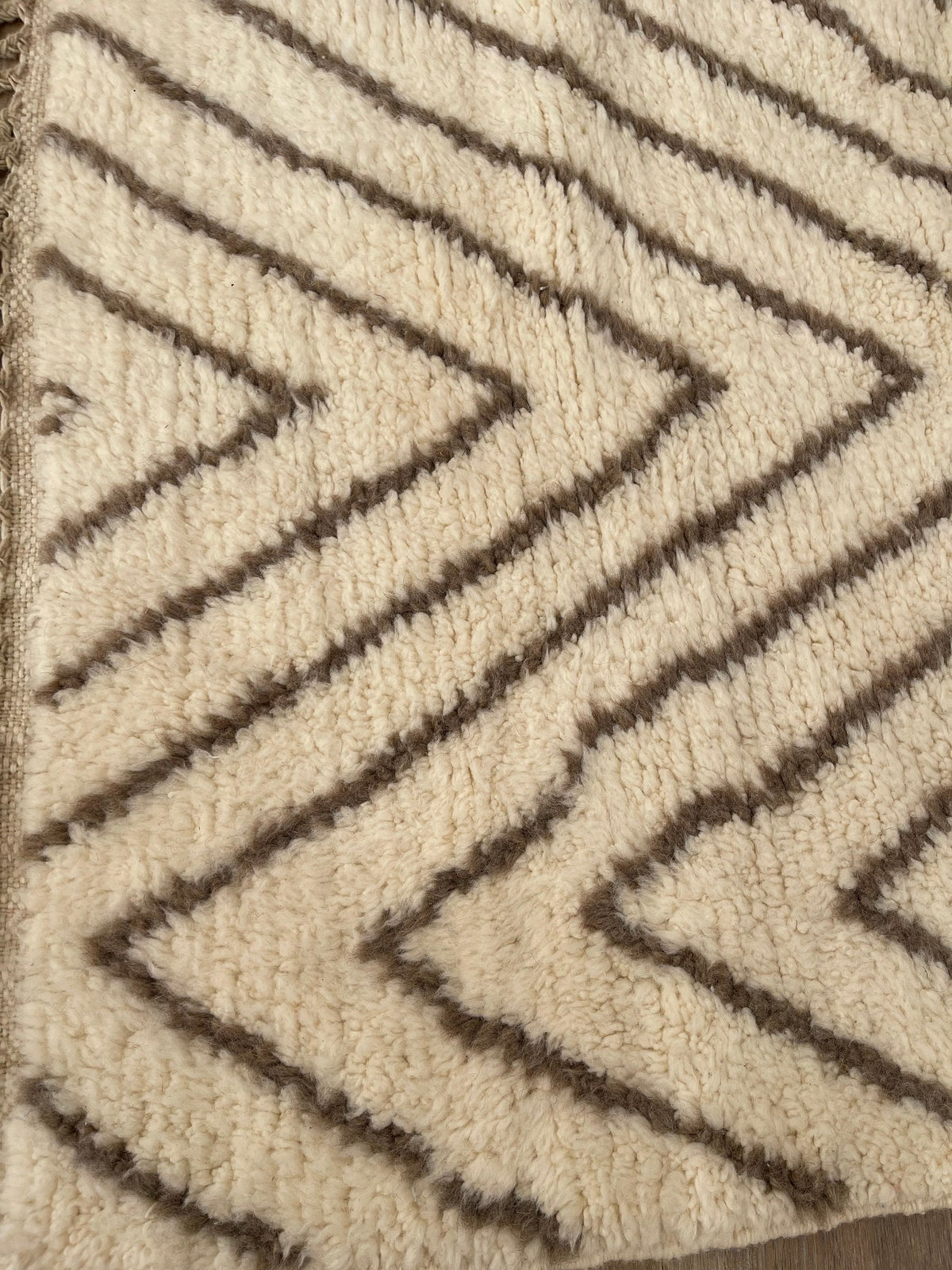 Gros plan sur la laine du tapis berbère Almis, nœuds serrés et tracé du motif de près