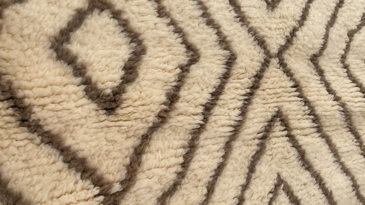 Gros plan sur la laine du tapis berbère Almis, poil blanc et taupe noué à la main