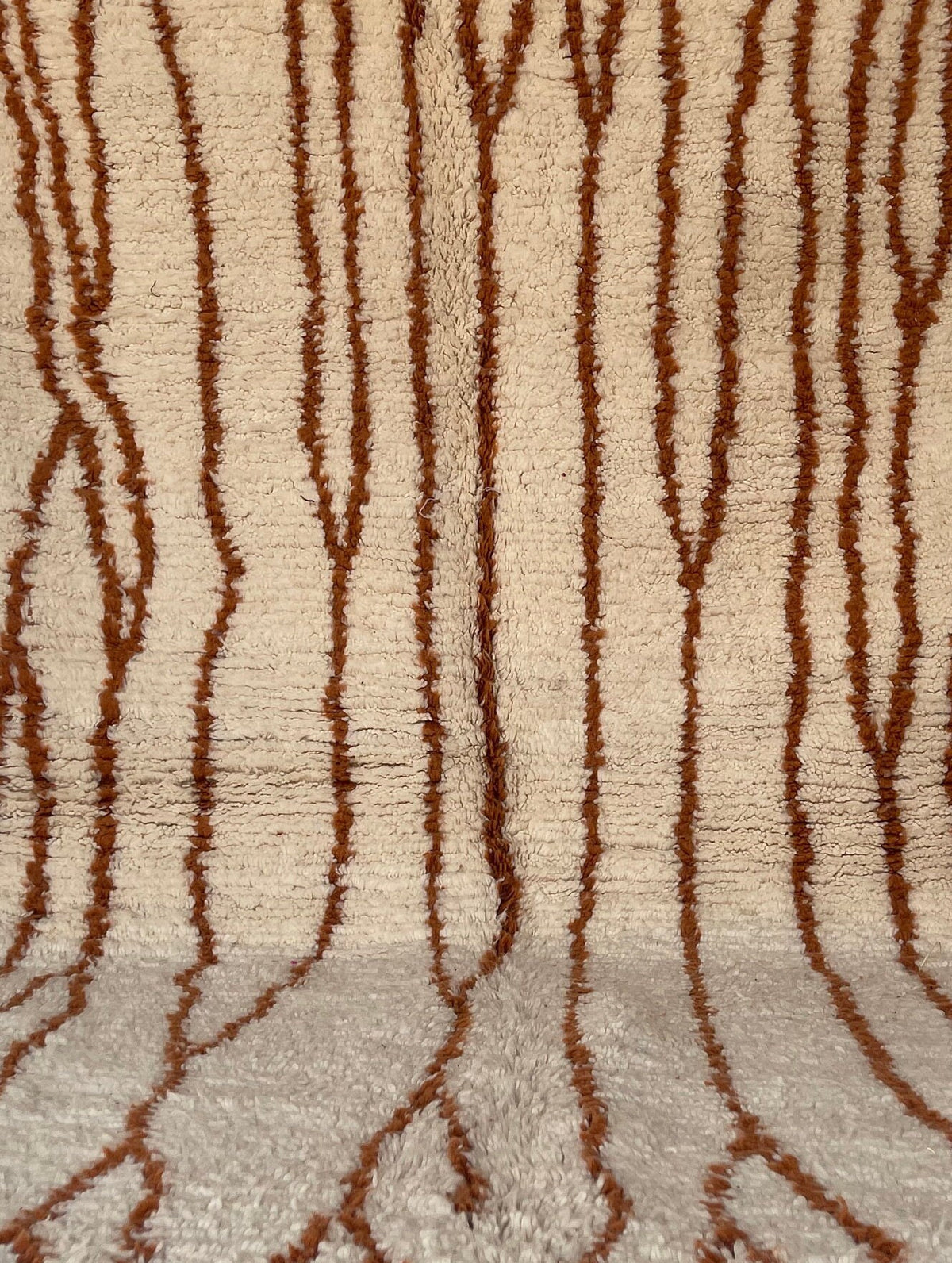 Gros plan sur la laine du tapis berbère Aghanim, laine de mouton au poil long, blanche et terracotta