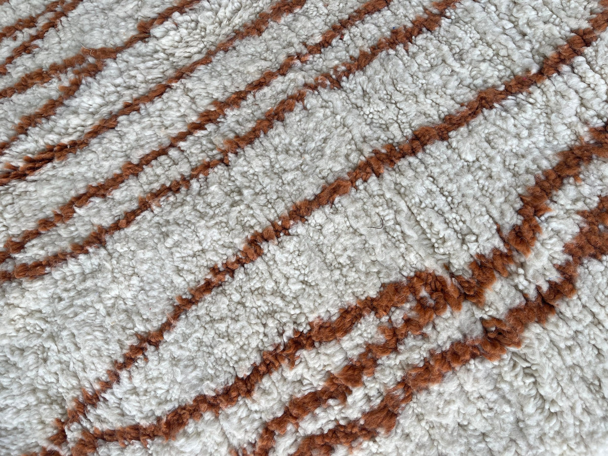 Gros plan sur la laine du tapis berbère Aghanim, nœuds serrés et tracé du motif de près