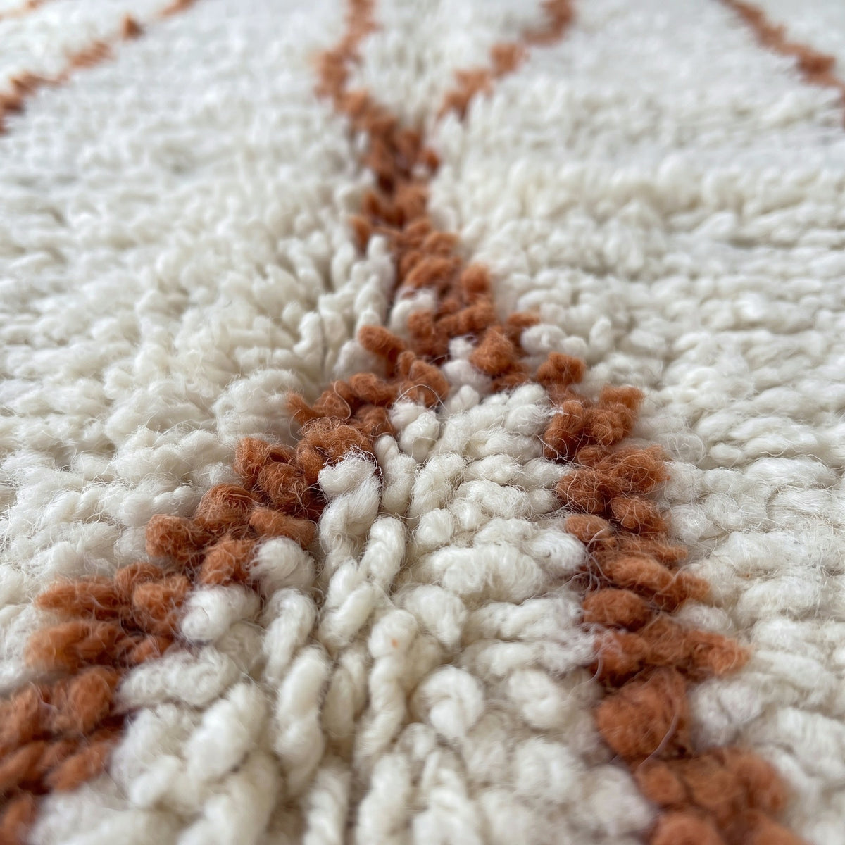 Gros plan sur un motif du tapis berbère Aghanim, fond écru à poil long, une douzaine