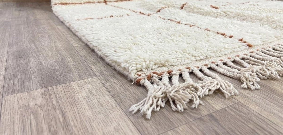 Tapis berbère style Beni Ouarain blanc et terracotta Talat posé au sol vu de côté, noué main au Maroc
