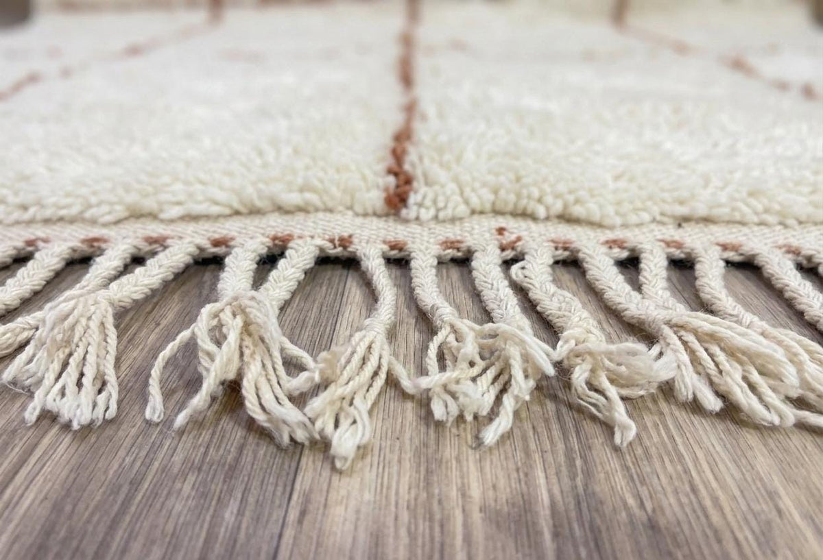 Gros plan sur les franges du tapis berbère Talat, écrues tressées, nouées à la main
