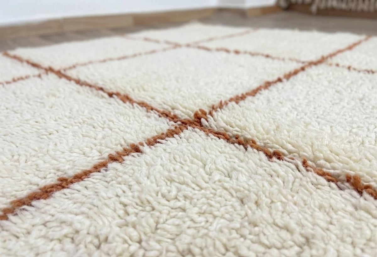 Gros plan sur la laine du tapis berbère Talat, laine de mouton au poil long, blanche et terracotta