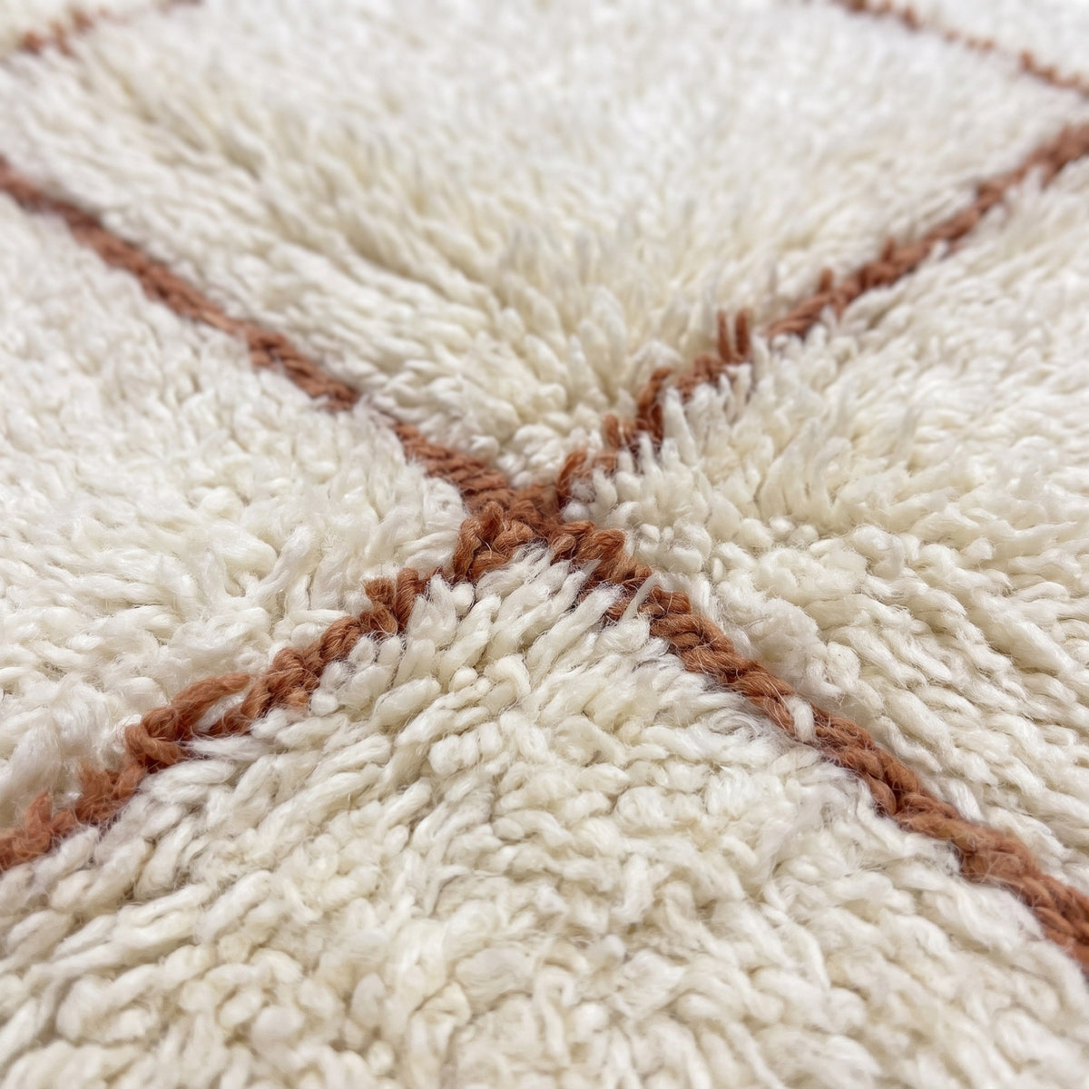 Gros plan sur un motif du tapis berbère Talat, fond ivoire à poil long et souple