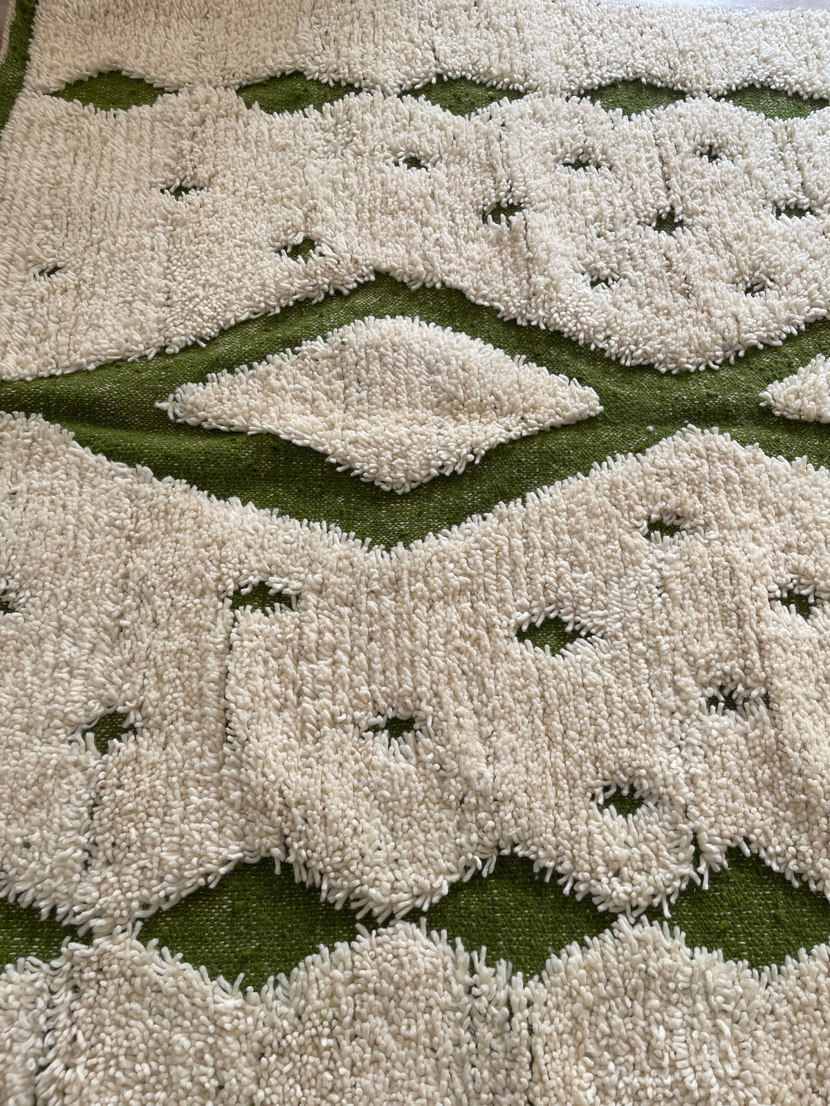 Gros plan sur un détail du tapis berbère Tahanaout, poil long et motif blanc et vert vus de près