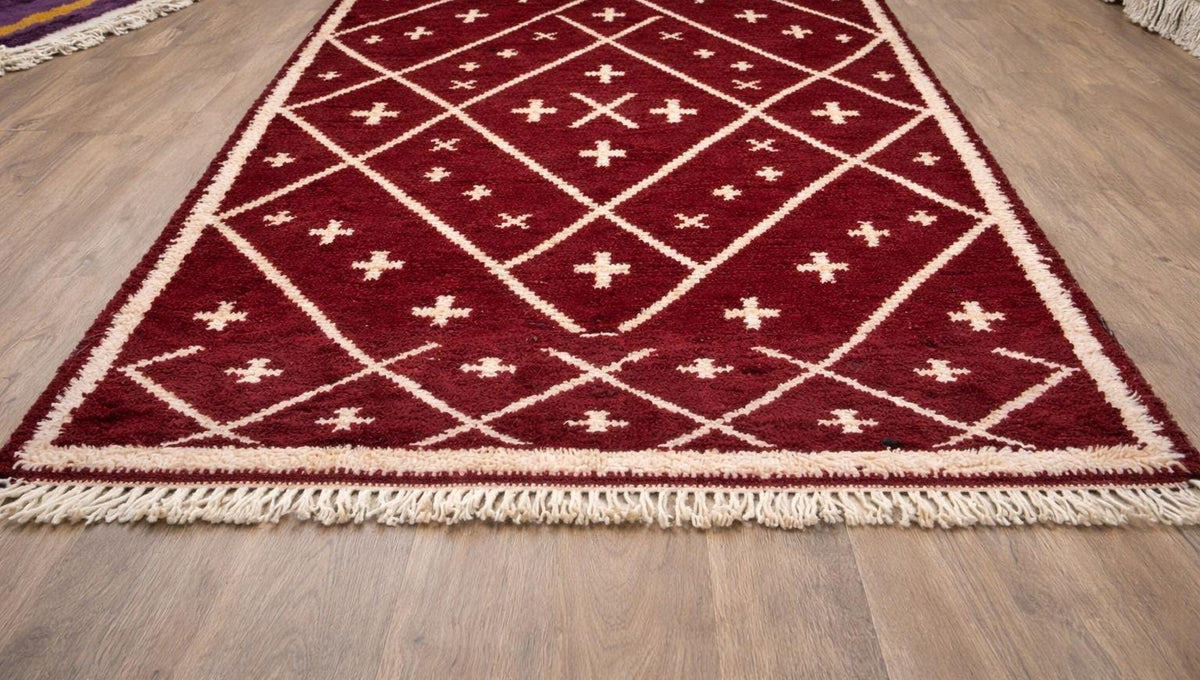 Tapis berbère style Beni Ouarain bordeaux Ammas posé au sol vu en biais, noué main au Maroc