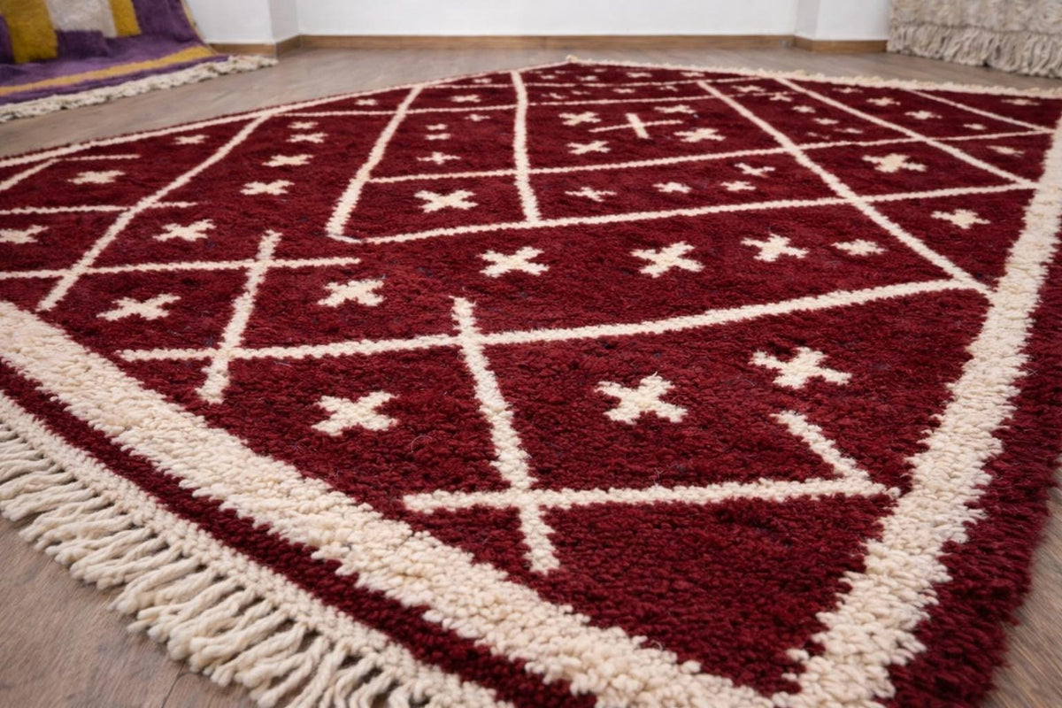 Gros plan sur un détail du tapis berbère Ammas, poil moyen et motif bordeaux vus de près