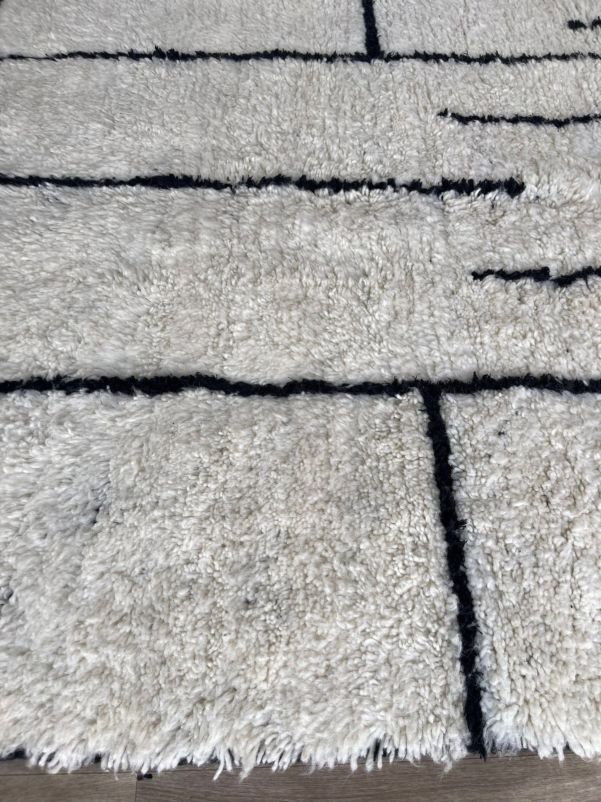 Gros plan sur les franges du tapis berbère Ilzoun, écrues en bas seulement, nouées à la main