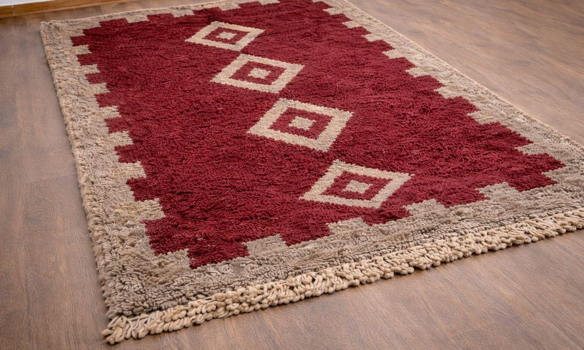 Tapis berbère style Boujad bordeaux et beige Tigejdit posé au sol vu de côté, noué main au Maroc
