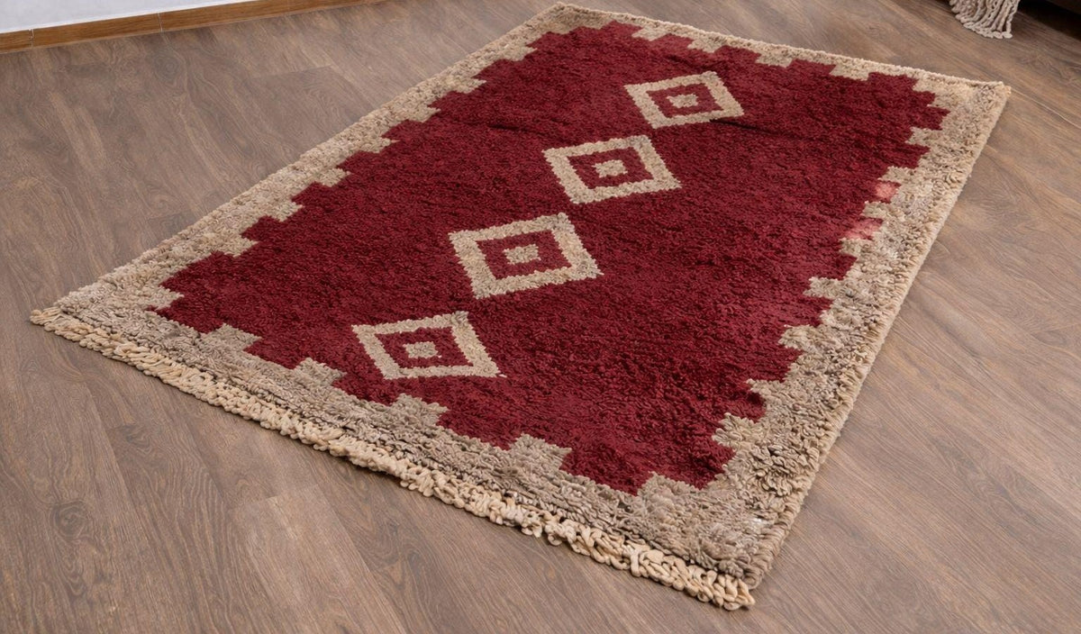 Tapis berbère style Boujad bordeaux et beige Tigejdit posé au sol vu de trois quarts, noué main au Maroc