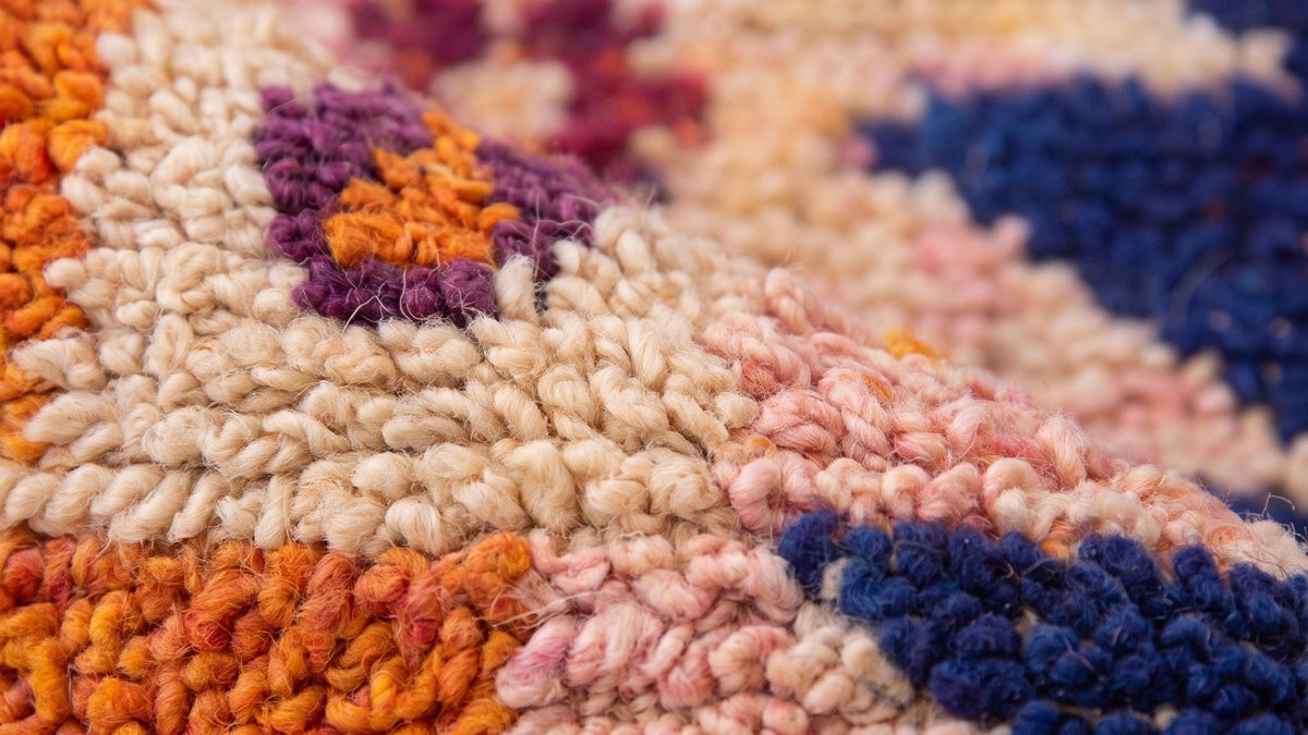 Gros plan sur la laine du tapis berbère Tafilalt, poil orange et bleu noué à la main