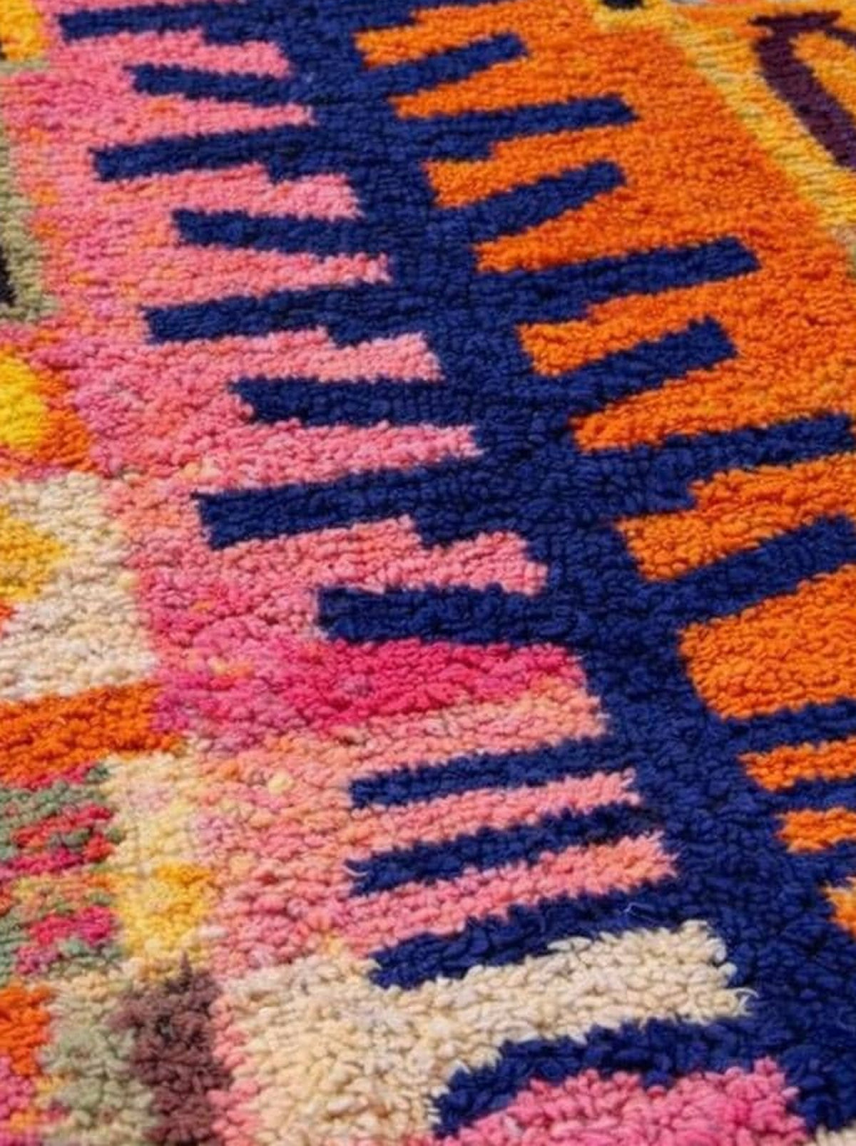 Tapis berbère style Boujad orange et rose Tazdayt posé au sol vu de côté, noué main au Maroc