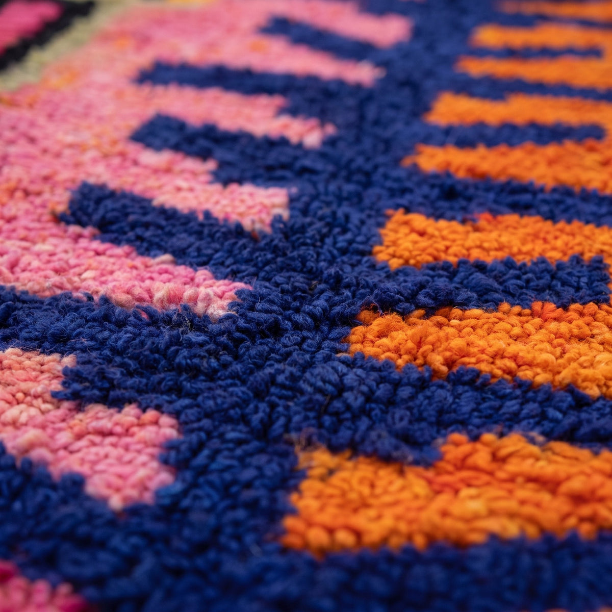 Gros plan sur un motif du tapis berbère Tazdayt, arête bleu marine ramifiée, champ rose à gauche