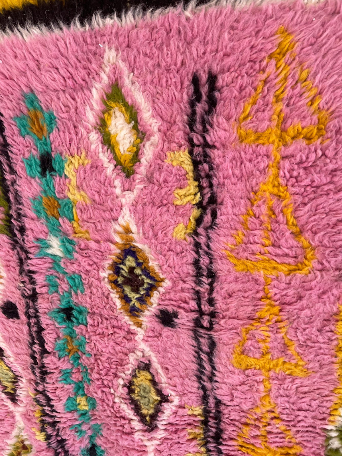 Gros plan sur la laine du tapis berbère Amezrou, nœuds serrés et tracé du motif de près