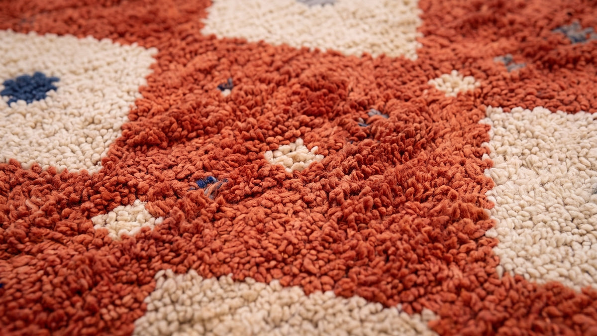 Gros plan sur la laine du tapis berbère Boukra, poil terracotta noué à la main