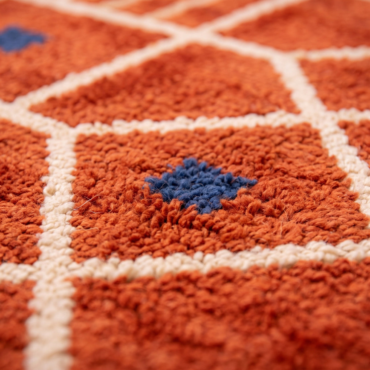 Close-up of a motif on the Tiznit Berber rug, terracotta ground with a grid of ecru lines