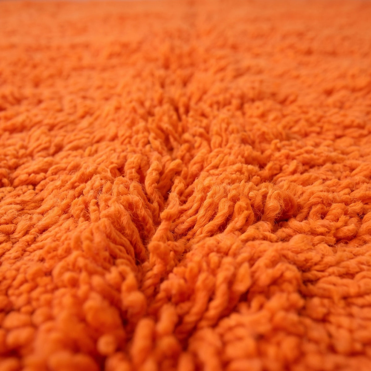 Close-up of a motif on the Merzouga Berber rug, plain bright orange field across the whole surface