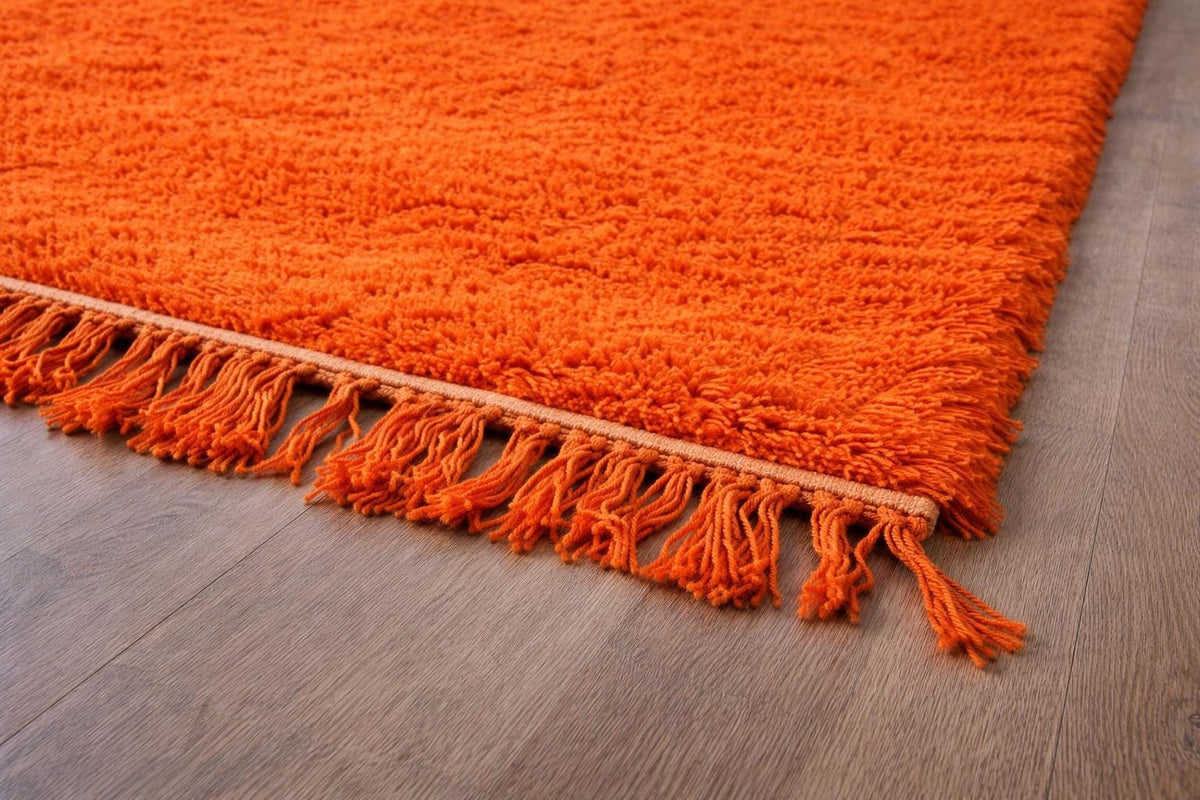 Gros plan sur la laine du tapis berbère Merzouga, poil orange noué à la main