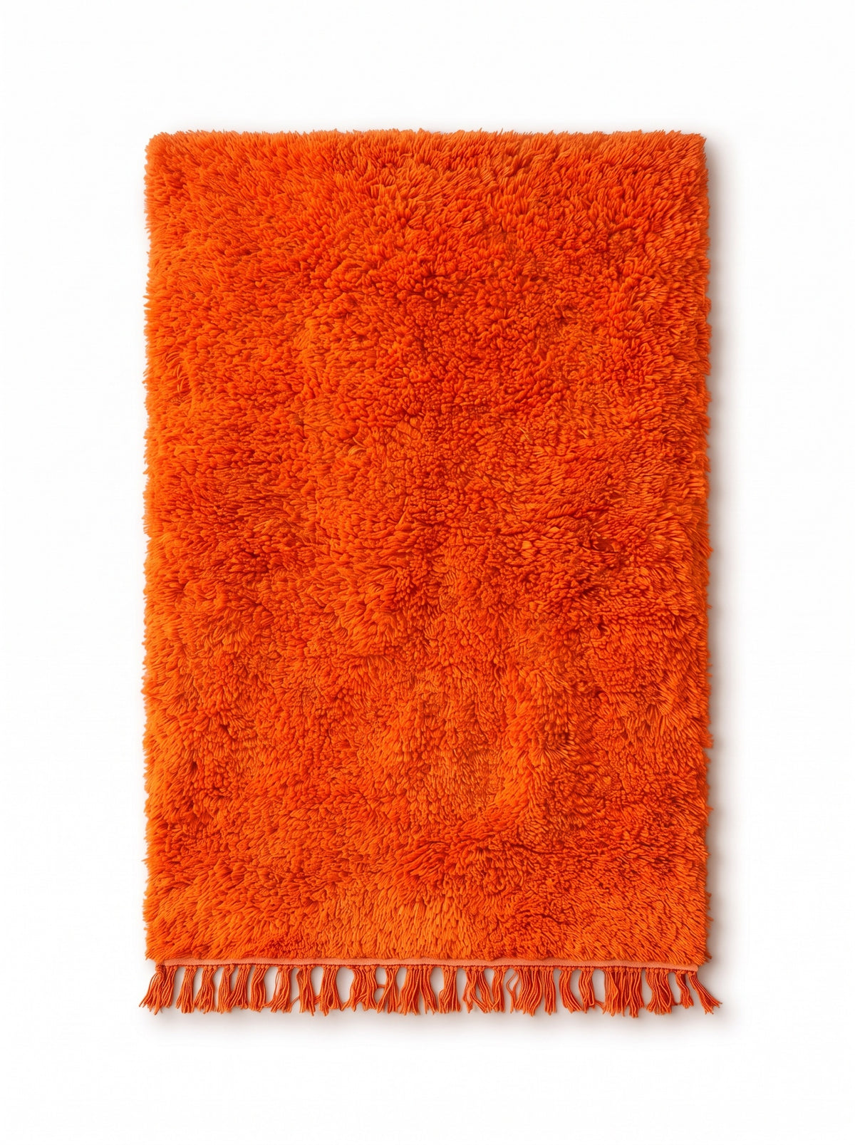 Merzouga plain orange Berber rug, laid flat, bright orange field throughout, orange fringes knotted at the bottom only