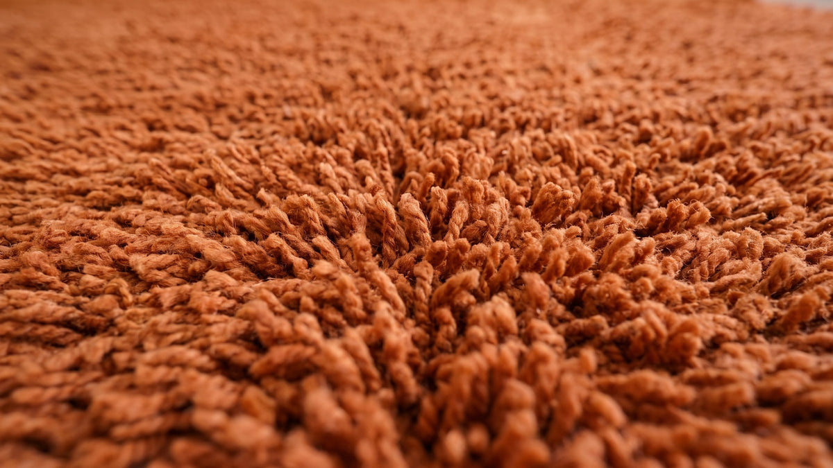 Gros plan sur la laine du tapis berbère Hagounia, poil terracotta noué à la main