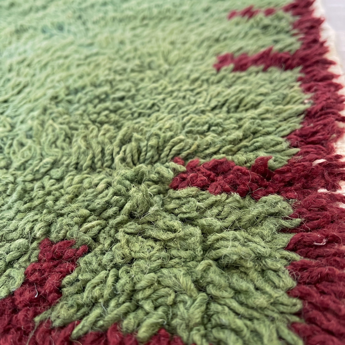 Gros plan sur un motif du tapis berbère Chrafate, champ vert olive uni à poil long