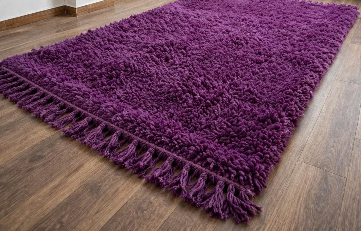 Tapis berbère uni violet prune Tazart posé au sol vu de côté, noué main au Maroc