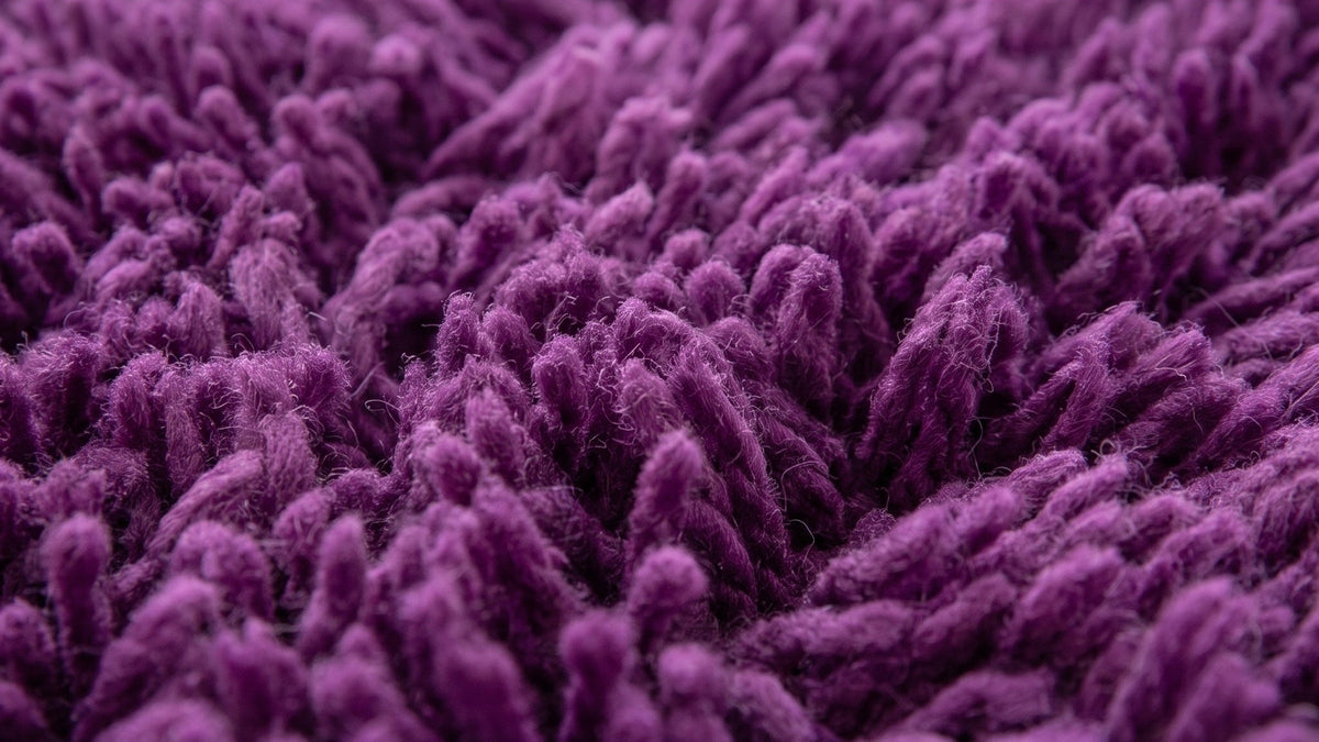 Gros plan sur la laine du tapis berbère Tazart, poil violet prune noué à la main