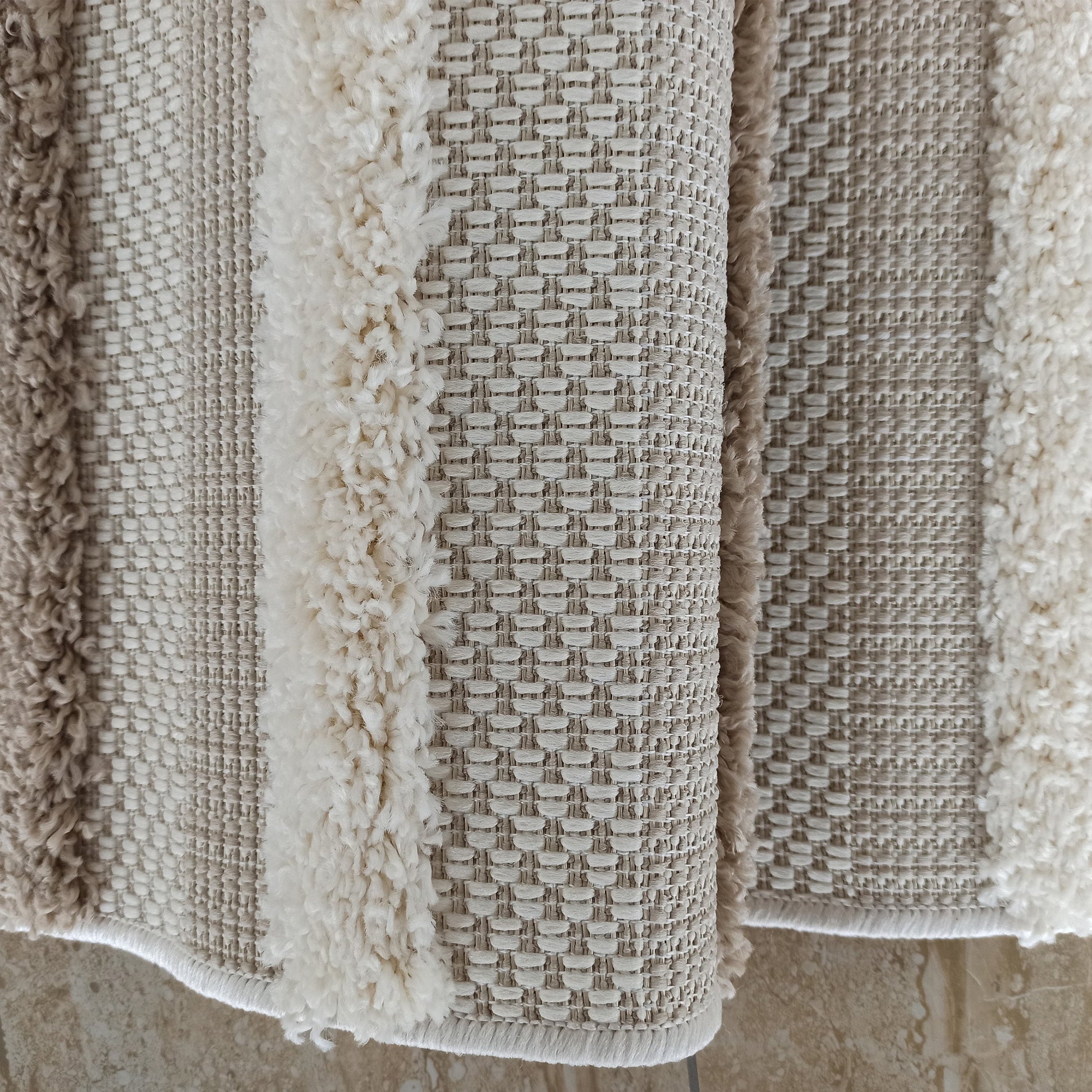 Tapis aux nuances de beige et crème, présentant des bandes de tissu bouclé et des zones au tissage régulier
