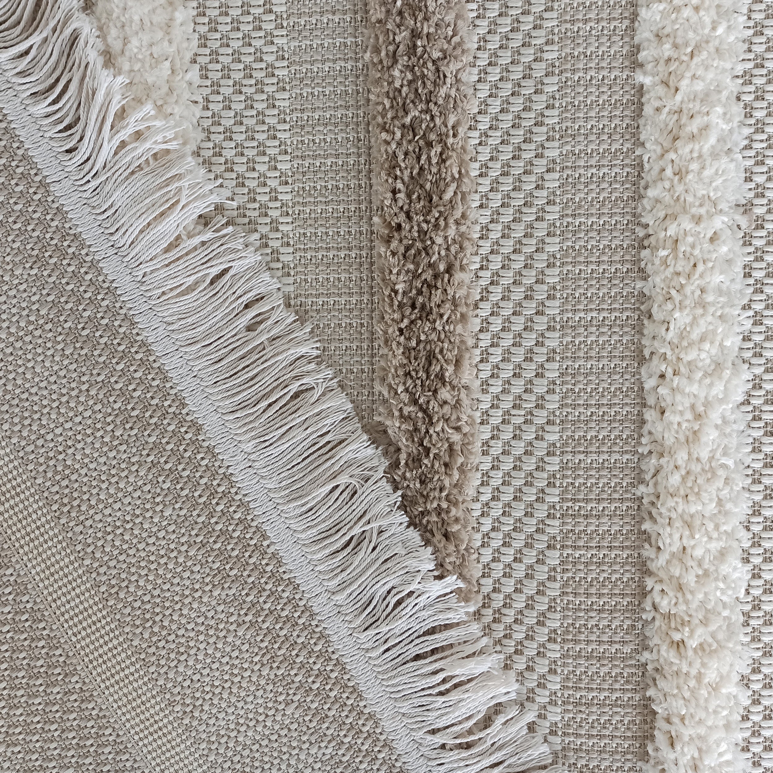 Tapis texturé avec des bandes shaggy crème et marron clair, et des franges blanches sur une base tissée beige